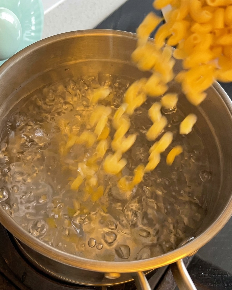 Trockene Makkaroni werden in einen Topf mit kochendem Wasser gegeben.