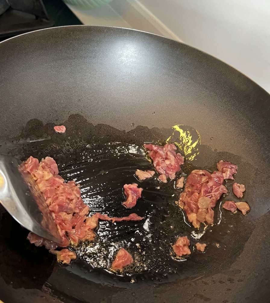 Rinderhackfleisch wird in einem heißen Wok angebraten.