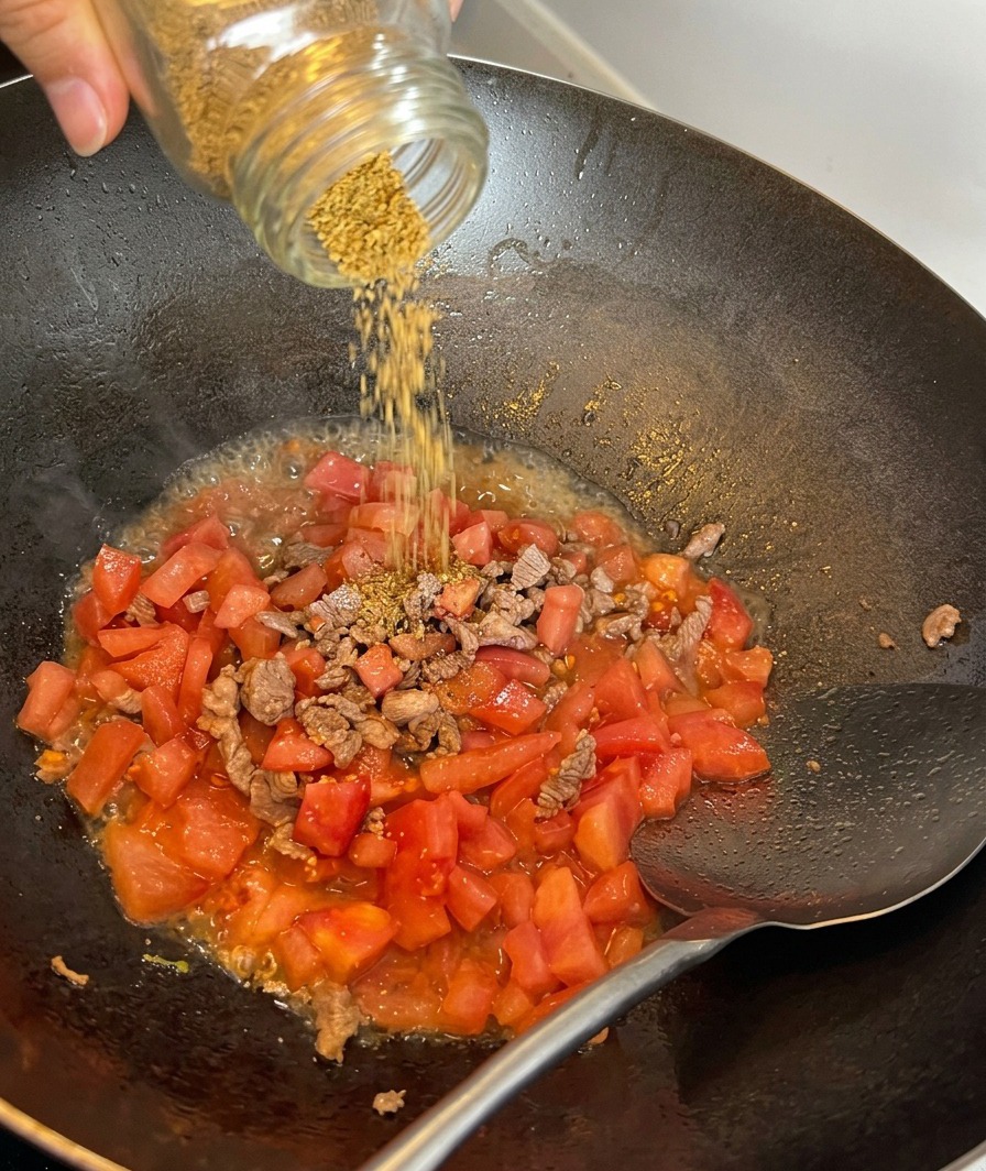 Meersalz wird über die Mischung aus Fleisch und Tomaten gestreut.