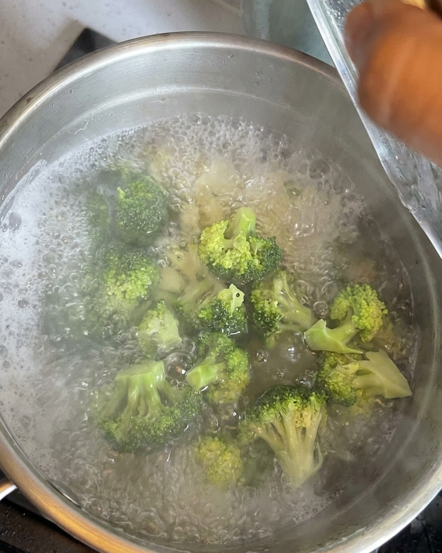 Grüne Brokkoli-Röschen kochen zusammen mit den Makkaroni im Topf.