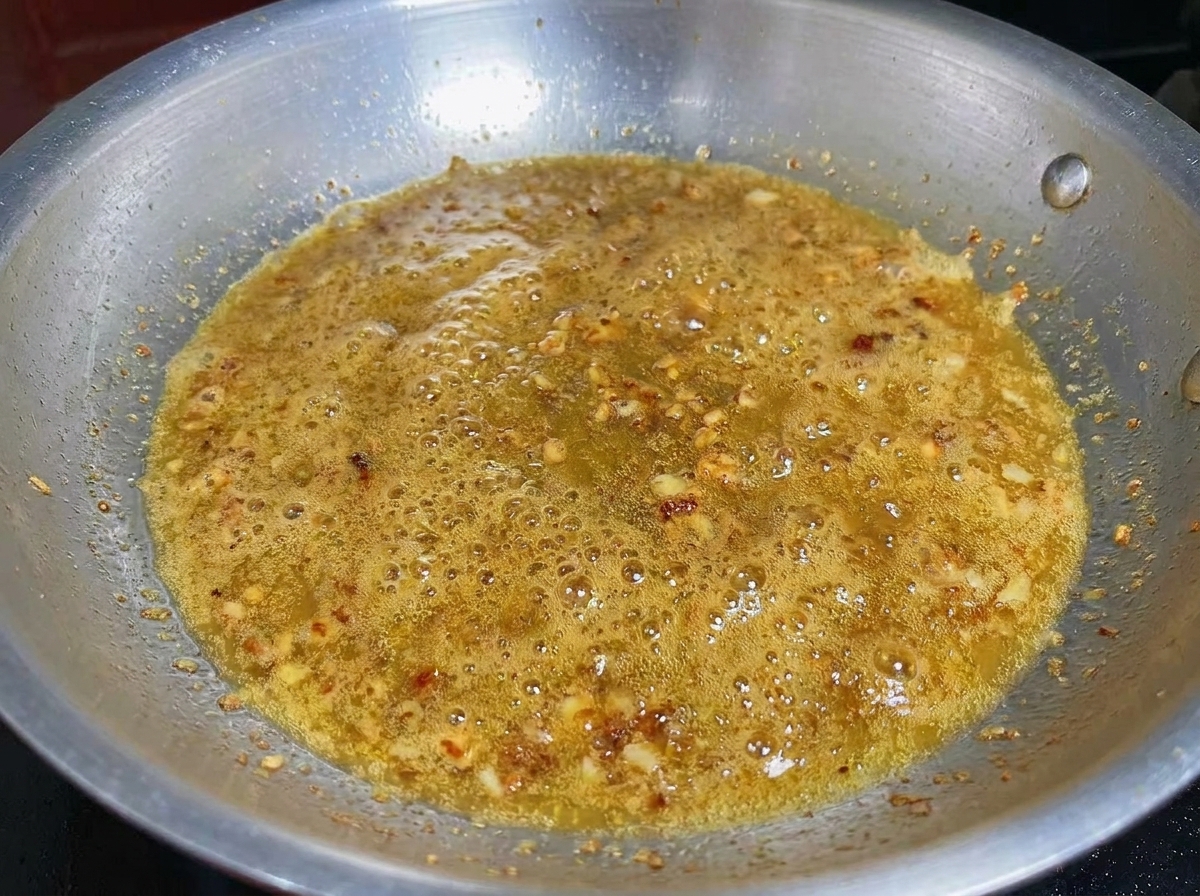 Gehackter Knoblauch und Garnelen kochen zusammen in einem aromatisierten Olivenöl.