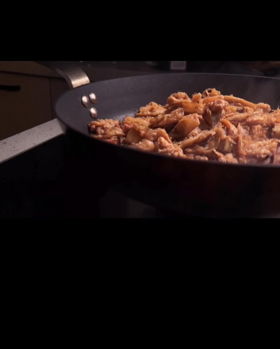 Spaghetti werden in der Pfanne mit der Fleischsauce geschwenkt.