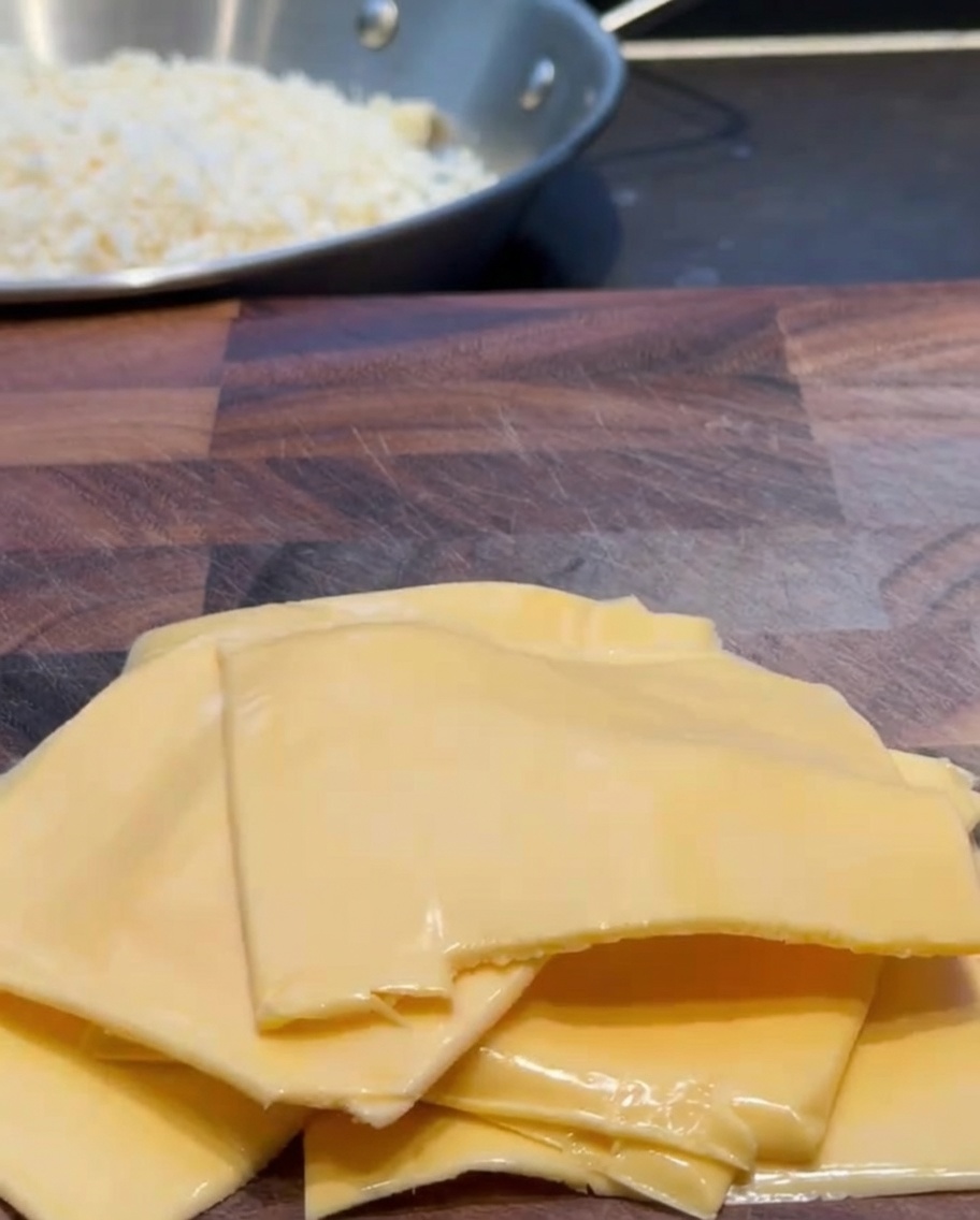 Cheddar-Käsescheiben werden auf einem Holzbrett in kleine Stücke geschnitten.