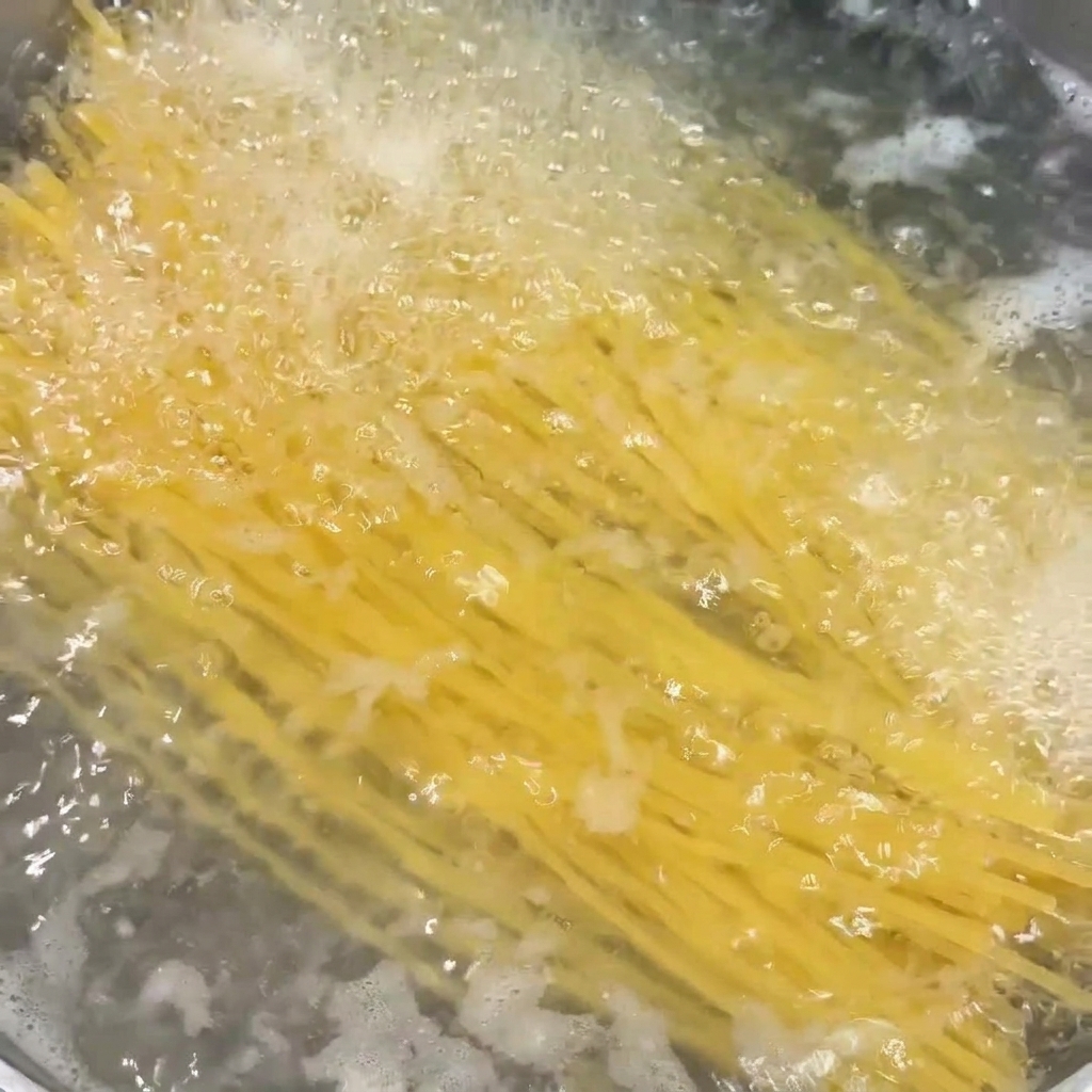 Spaghetti-Nudeln kochen in einem Topf mit stark sprudelndem Wasser.