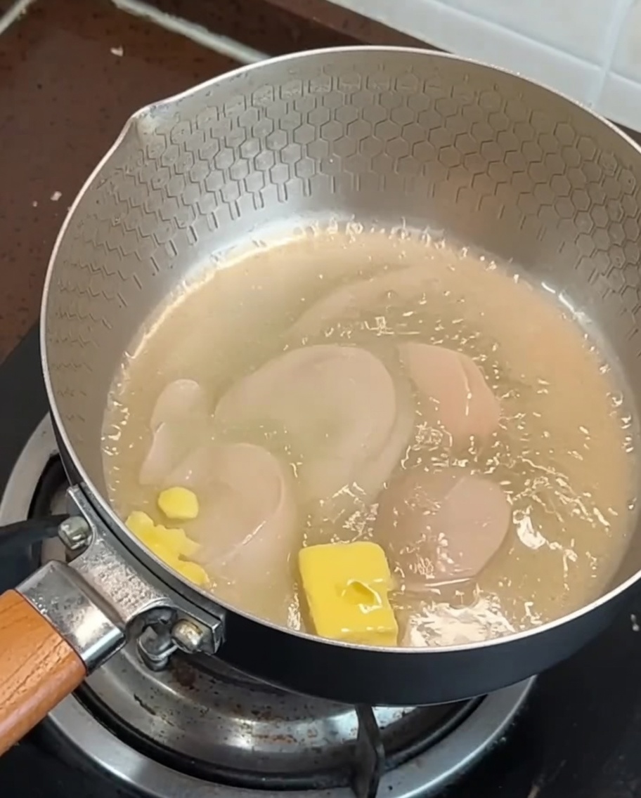 Speck- und Knoblauchscheiben, die in einer Pfanne mit schmelzender Butter braten.