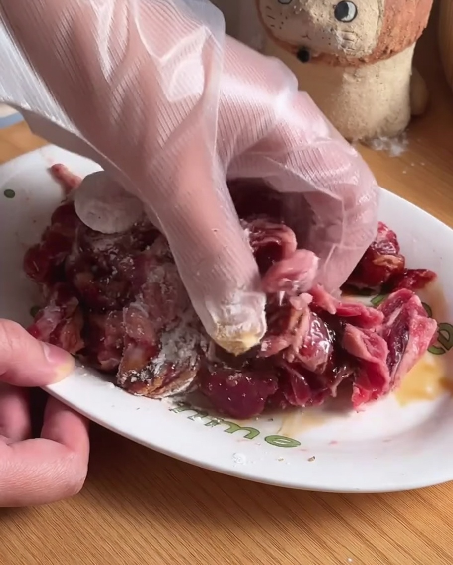 Rinderstreifen werden in einer weißen Schüssel mit Gewürzen und Marinade vermengt.