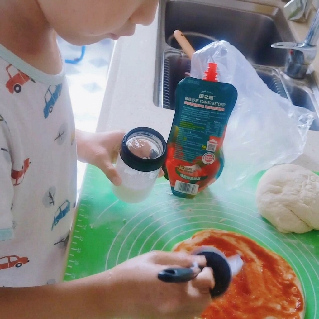 Salz wird über die Tomatensoße auf dem Pizzateig gestreut.