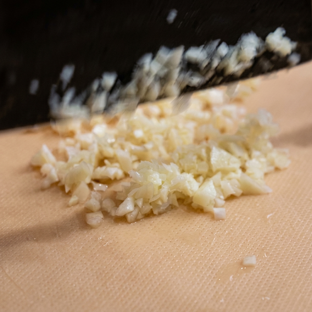Fein gehackte Knoblauchstücke auf einem Schneidebrett.