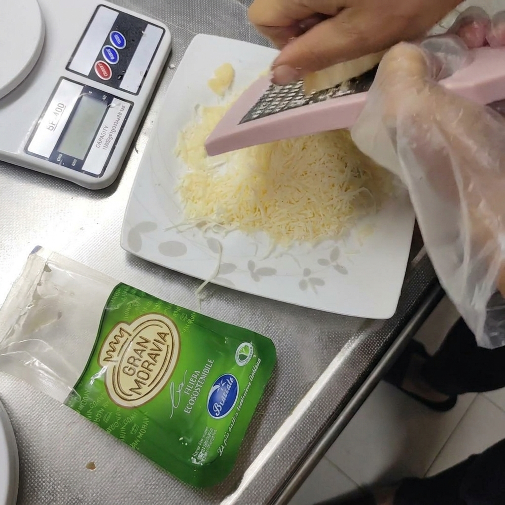 Gran Moravia Hartkäse wird auf einen kleinen Teller gerieben.