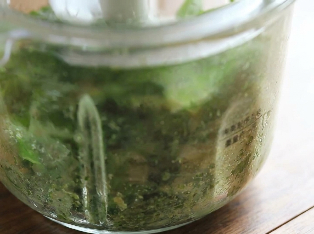 Nahaufnahme des Mixers mit dem frisch pürierten, leuchtend grünen Basilikum-Pesto.