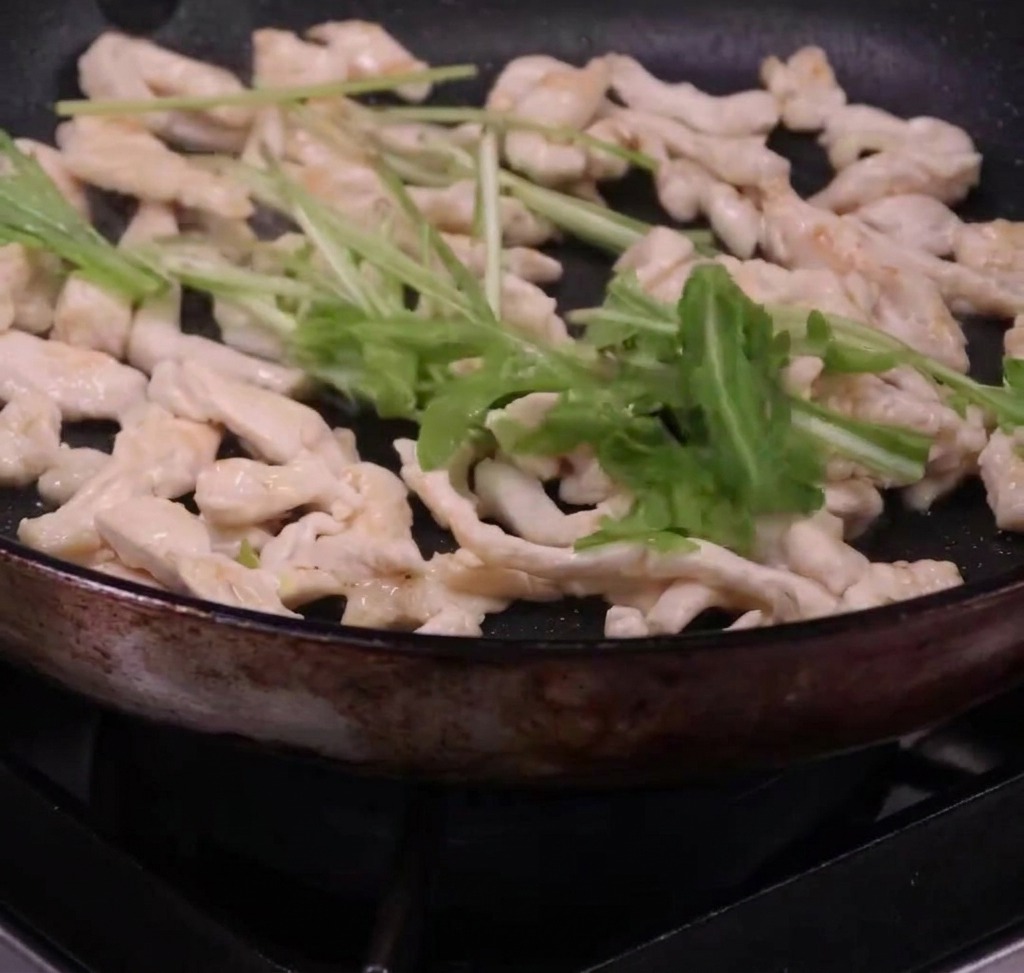 Spaghetti und Rucola werden in der Pfanne mit dem Hähnchen vermengt.