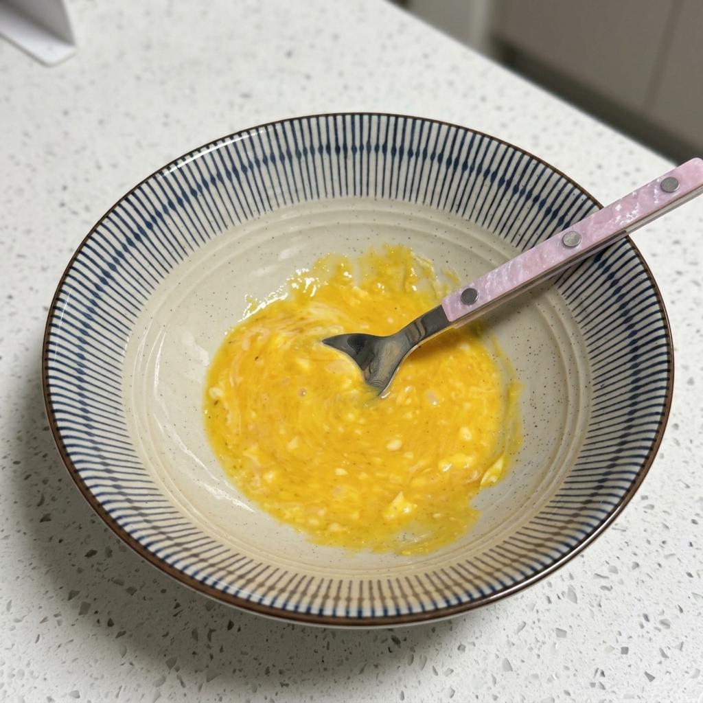 Eine Schüssel mit einer gelben, cremigen Brühenbasis wird mit einem Löffel gerührt.