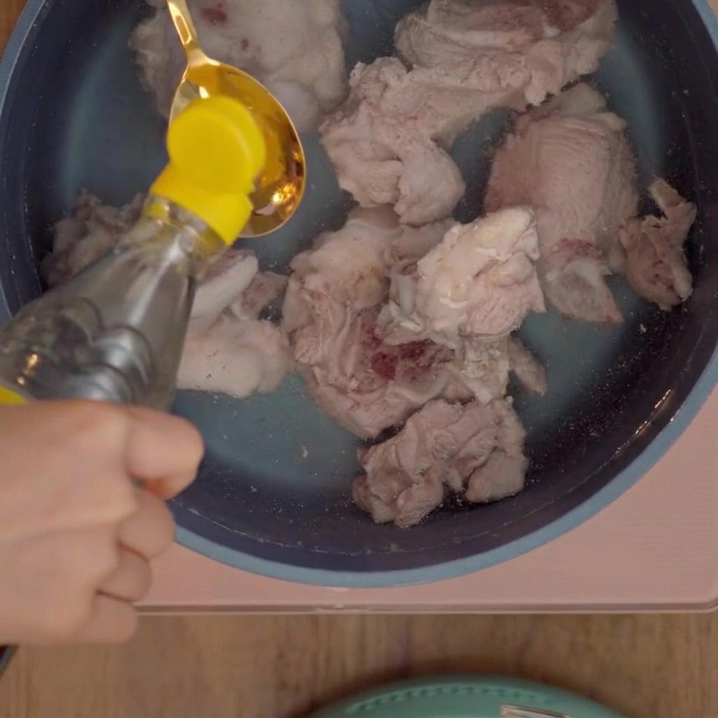 Ein Esslöffel weißer Essig wird in den Topf zu den Schweineknochen gegeben.