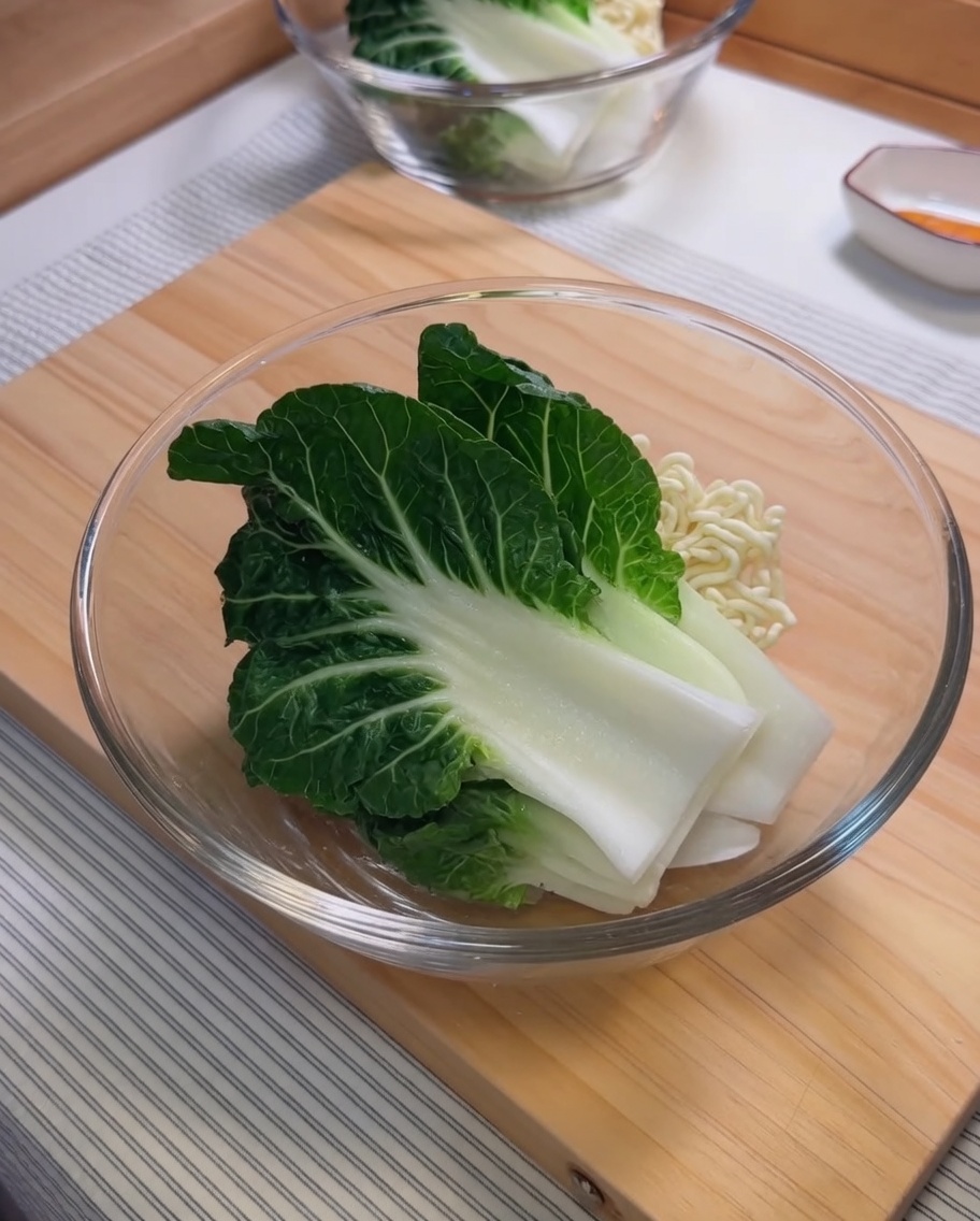 Zutaten für die Sesamsauce, darunter Sesampaste und Chiliöl, werden in einer Glasschüssel vermengt.