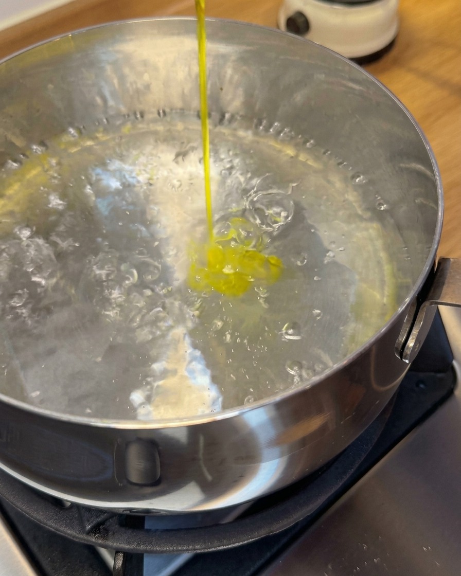 Rohe Garnelen-Wan-Tans werden mit einem Schaumlöffel in einen Topf mit kochendem Wasser gegeben.