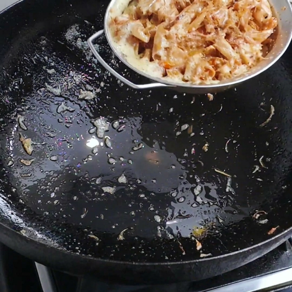 Heißes Wasser wird in einen Wok mit Garnelenschalen gegossen, um eine aromatische Brühe zu erzeugen.