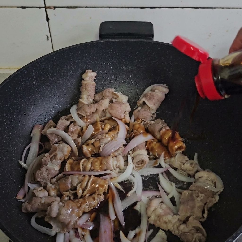 Rindfleisch und Zwiebeln werden in einer heißen Pfanne mit Sauce geschwenkt.