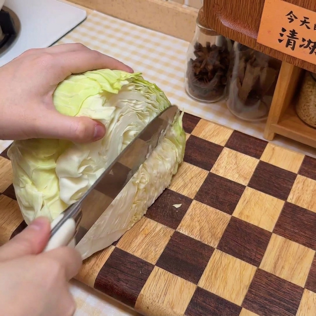 Ein Kohlkopf, der auf einem Holzbrett in Streifen geschnitten wird.