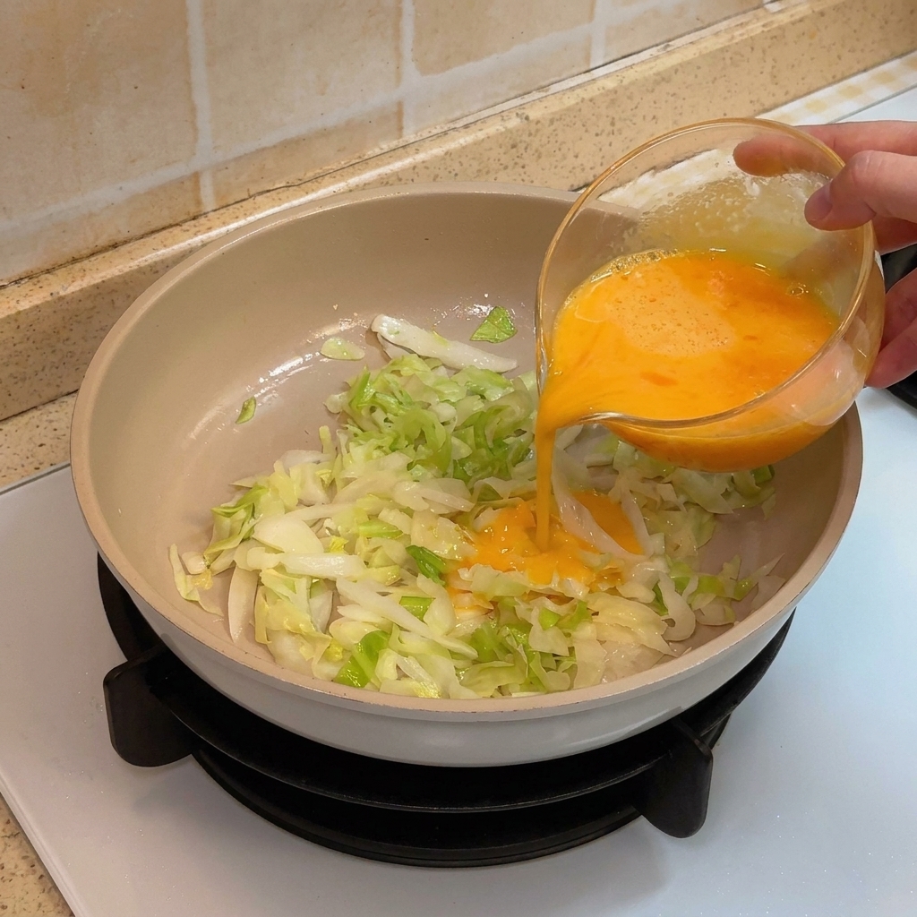 Eier werden in die Pfanne über den gebratenen Kohl gegeben.