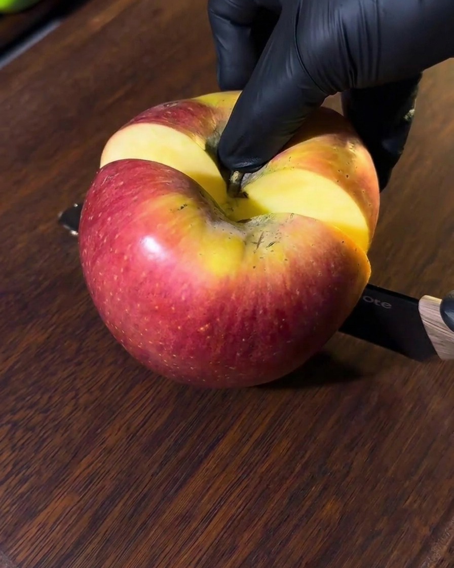Ein Apfel wird auf einem Holzbrett in kleine Stücke geschnitten.
