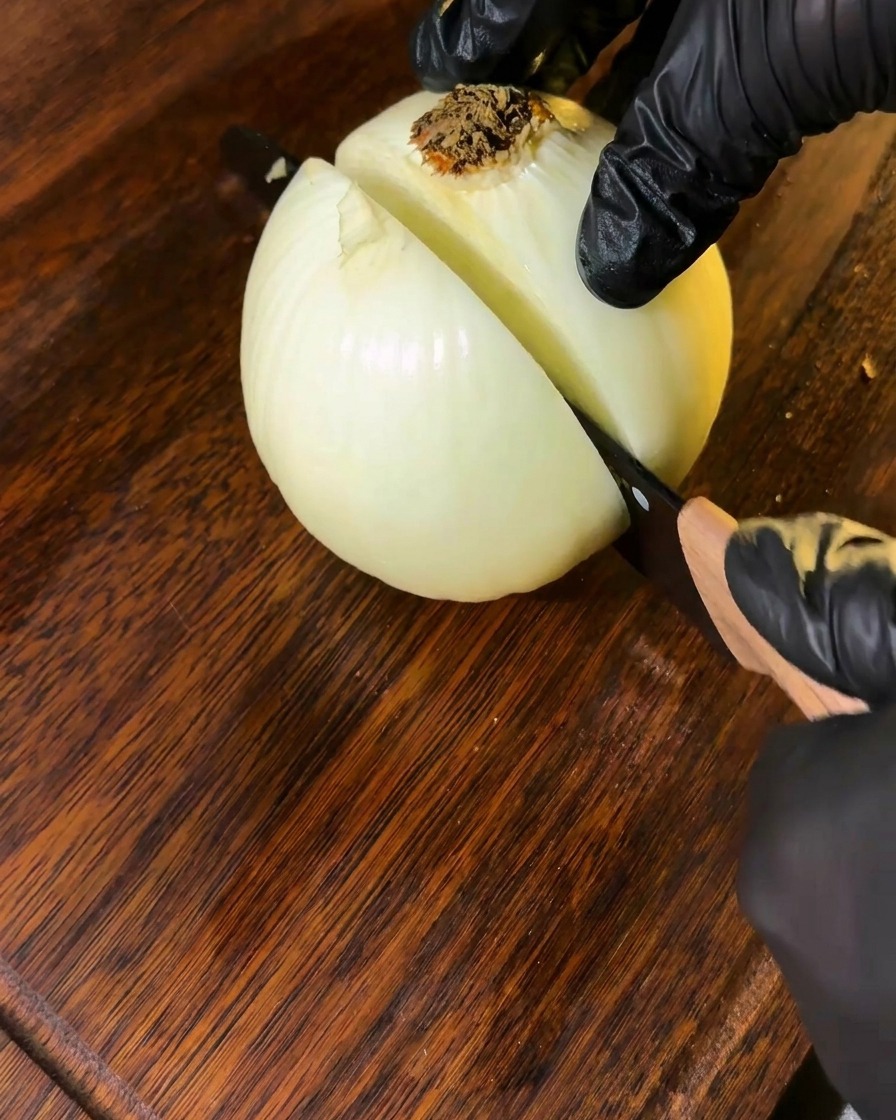 Eine Zwiebel wird auf einem Holzbrett in Stücke geschnitten.