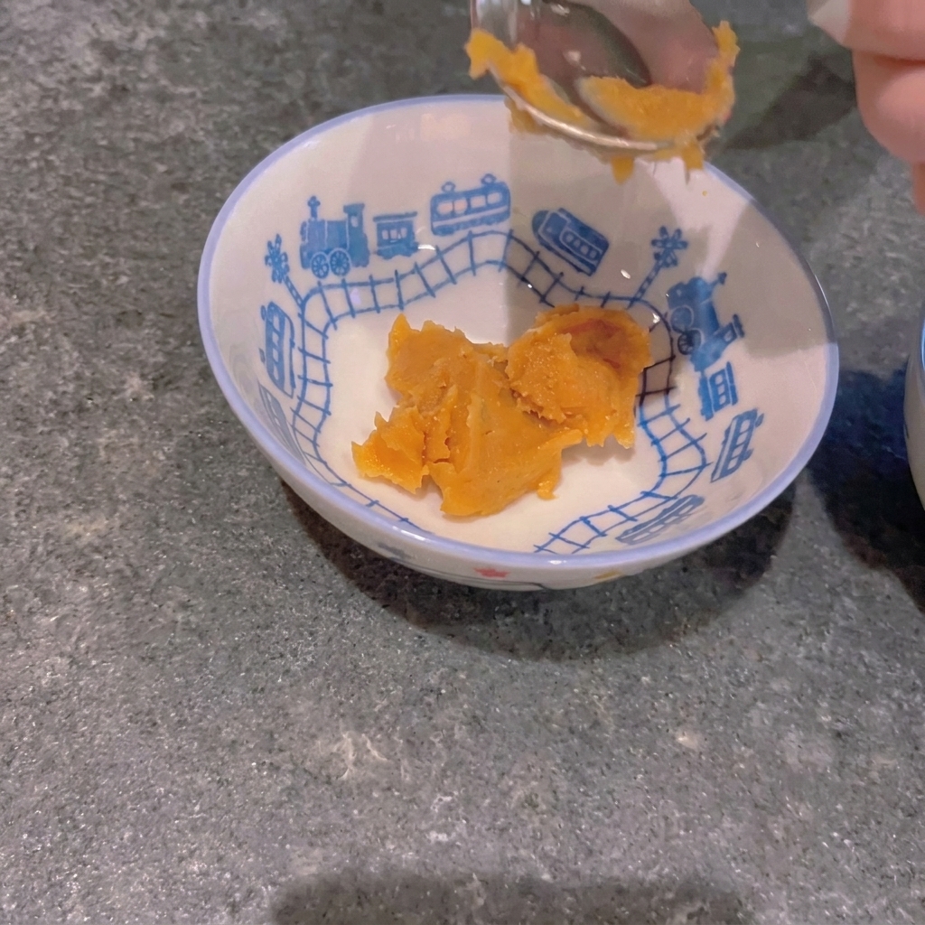 Ein Löffel gelbe Miso-Paste wird in eine kleine Schale mit Zugmuster gegeben.
