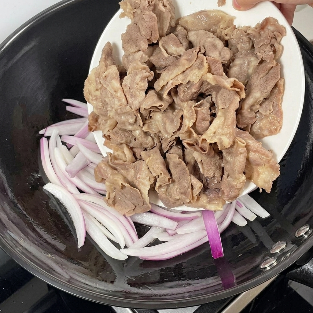 Blanchiertes Rindfleisch wird zu den angebratenen Zwiebeln in die Pfanne gegeben.