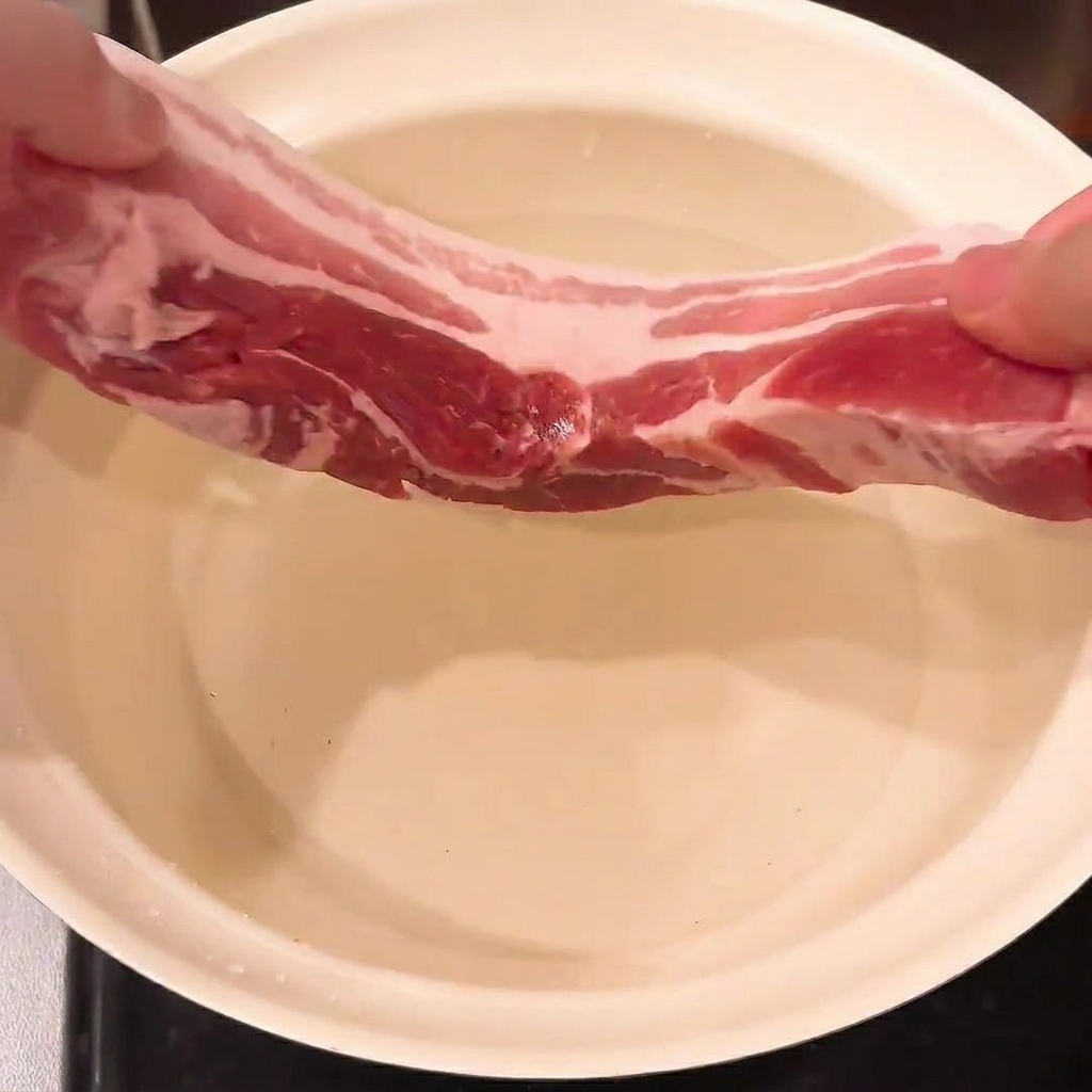 Schweinebauch, Frühlingszwiebel und Ingwer in einem Topf mit Wasser, bereit zum Blanchieren.
