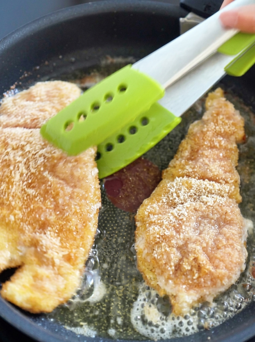 Hände dehnen eine rohe, eingeritzte Garnele, um sie länger zu machen.