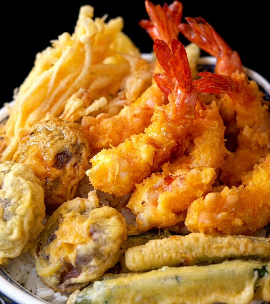 Eine fertige Tempura-Reisschale, belegt mit knusprig frittierten Garnelen und Gemüse.