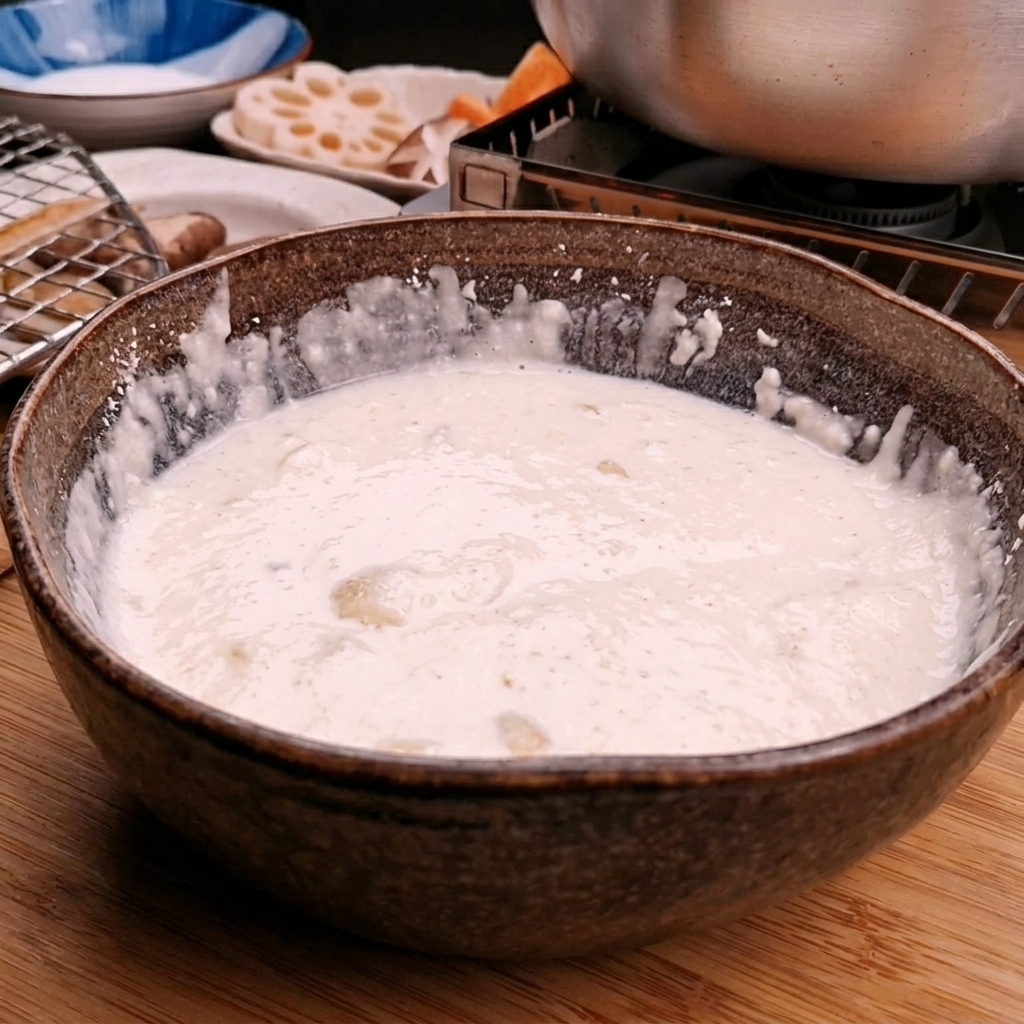 Eiswasser wird in eine Schüssel mit Tempura-Mehl gegossen, um einen glatten Teig zu rühren.