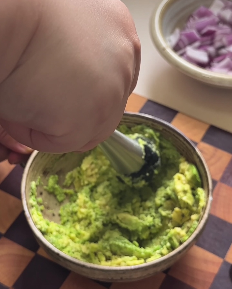 Avocado-Fruchtfleisch wird in einer Schüssel zu einer Paste zerdrückt.