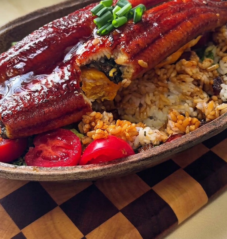 Nahaufnahme, wie Teriyaki-Zwiebelsauce über einen Reisberg gelöffelt wird.