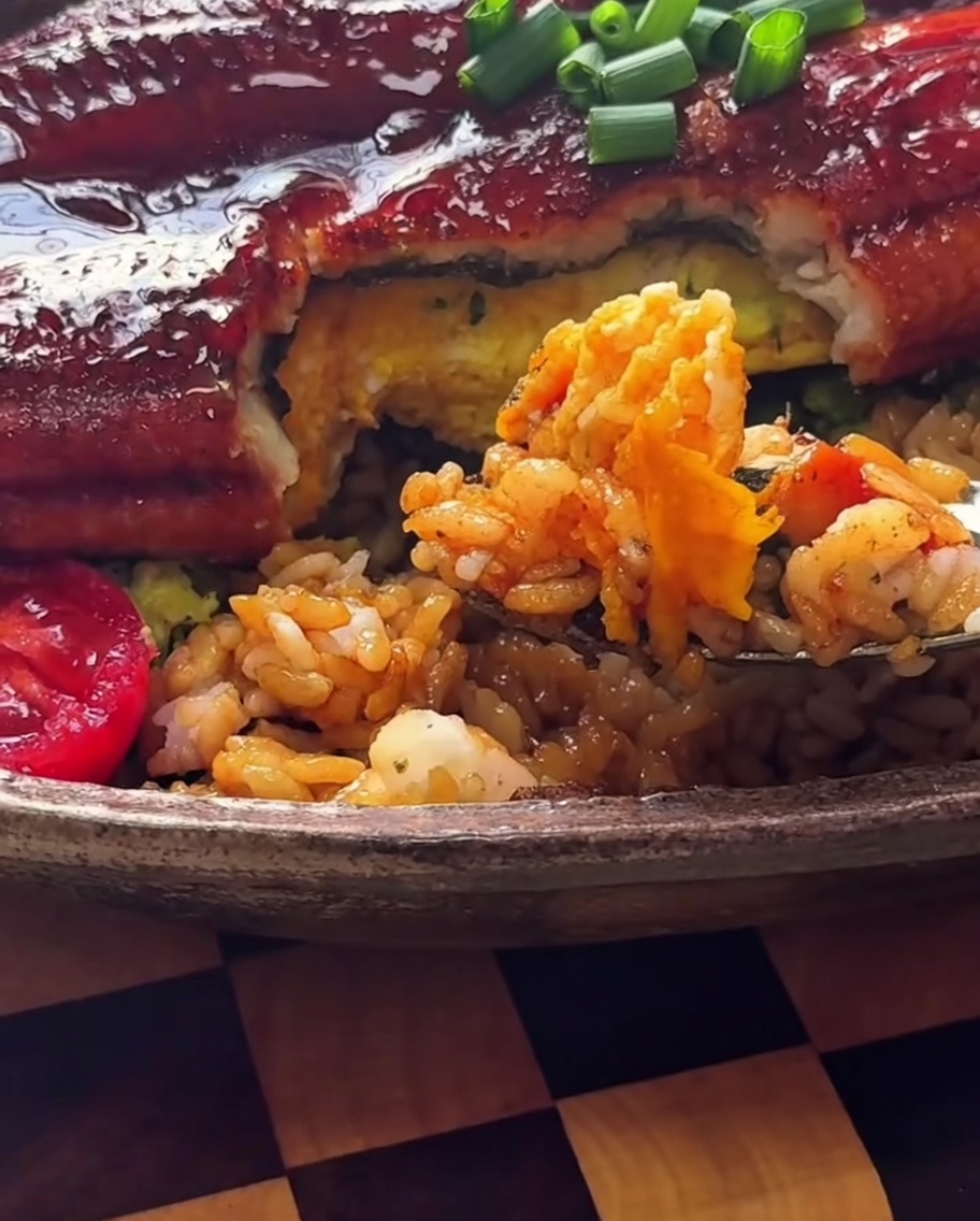 Nahaufnahme einer Schüssel mit Reis und Avocado, die mit Algenflocken bestreut wird.
