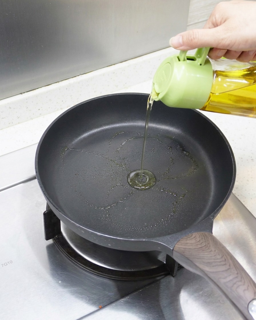 Nahaufnahme von Öl, das in eine vorgeheizte Antihaft-Pfanne gegeben wird, bereit für den Aal.