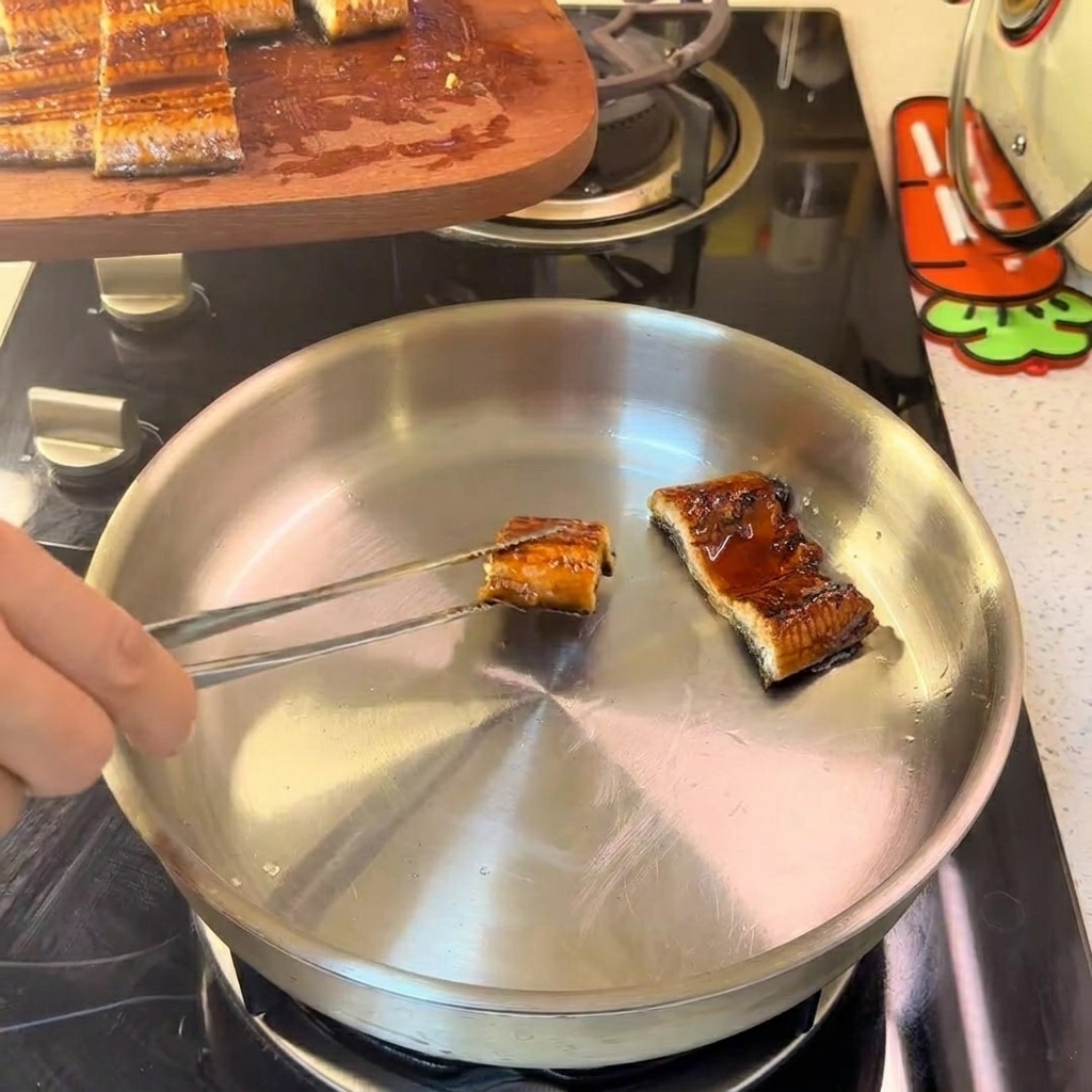 Aalstücke in einer Edelstahlpfanne, die sanft bei kleiner Flamme angebraten werden.