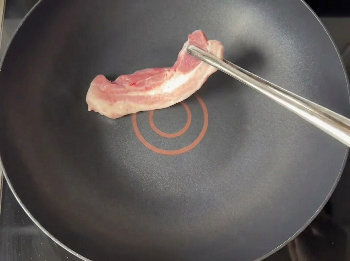 Goldbraune Schweinebauchscheiben braten in einer trockenen Pfanne.