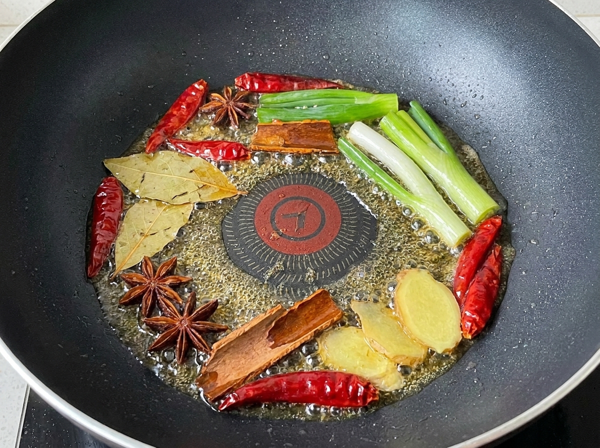 Frühlingszwiebeln, getrocknete Chilis und Gewürze in Öl gebraten.