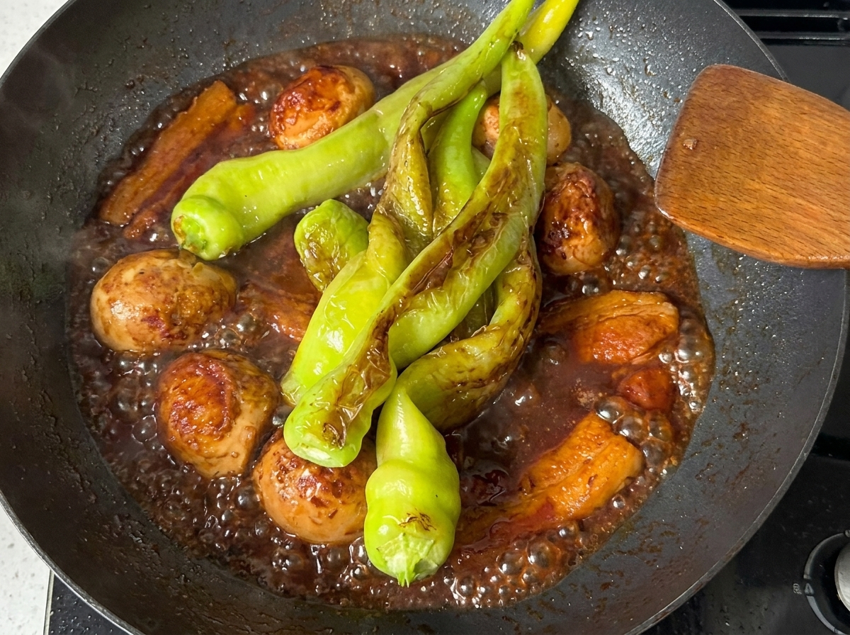 Grüne Paprika schmoren in der dunklen, reichhaltigen Sauce mit Schweinebauch.
