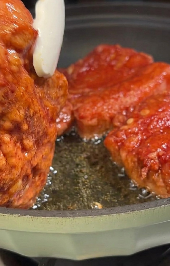 Schweinebauchstreifen braten in einer Pfanne und nehmen eine goldbraune Farbe an.