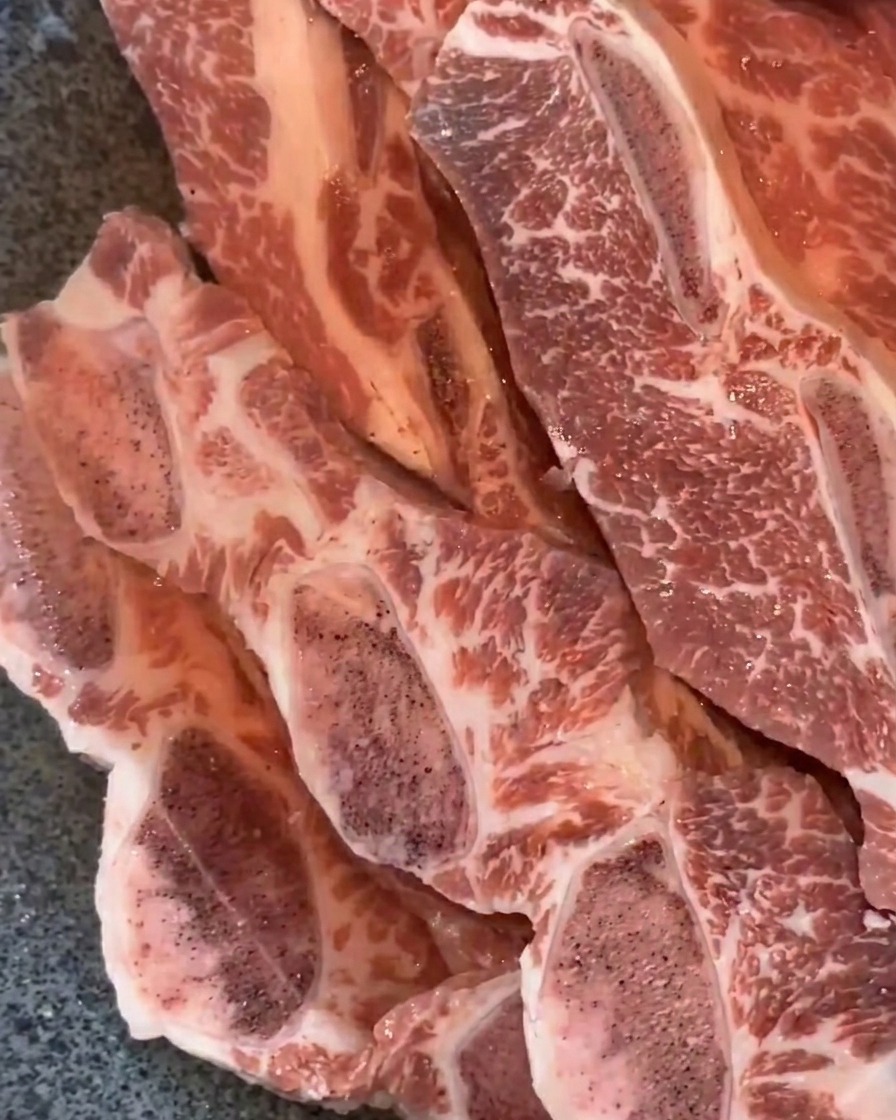 Rinder-Short-Ribs, die in einer Metallpfanne in Wasser eingeweicht werden.