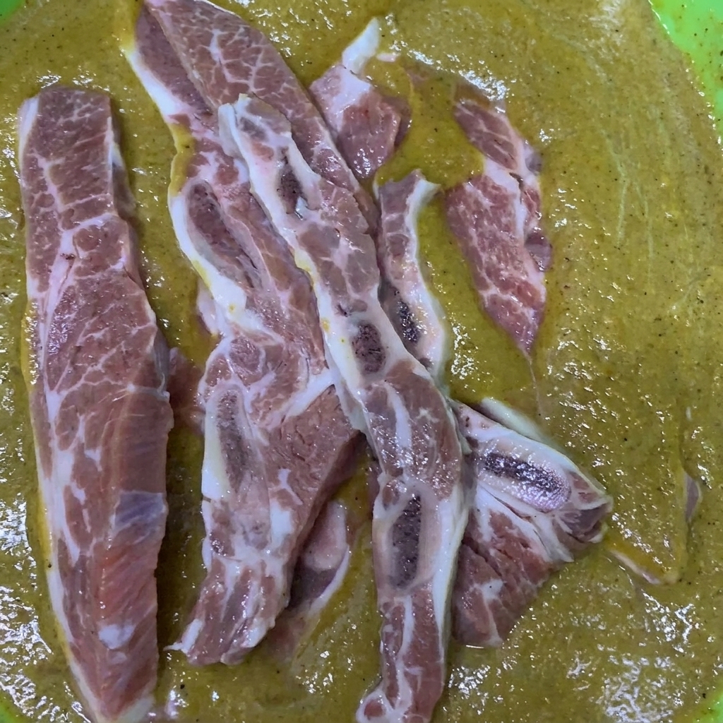 Rinder-Short-Ribs werden in einer mit der koreanischen Marinade gefüllten Schüssel umgerührt und überzogen.