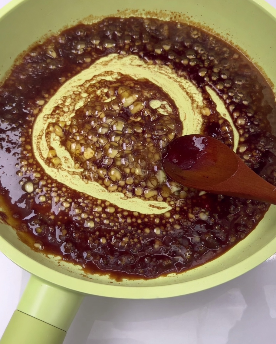 Gebratene Schweinerippchen werden in einer dunklen Sauce in der Pfanne glasiert.