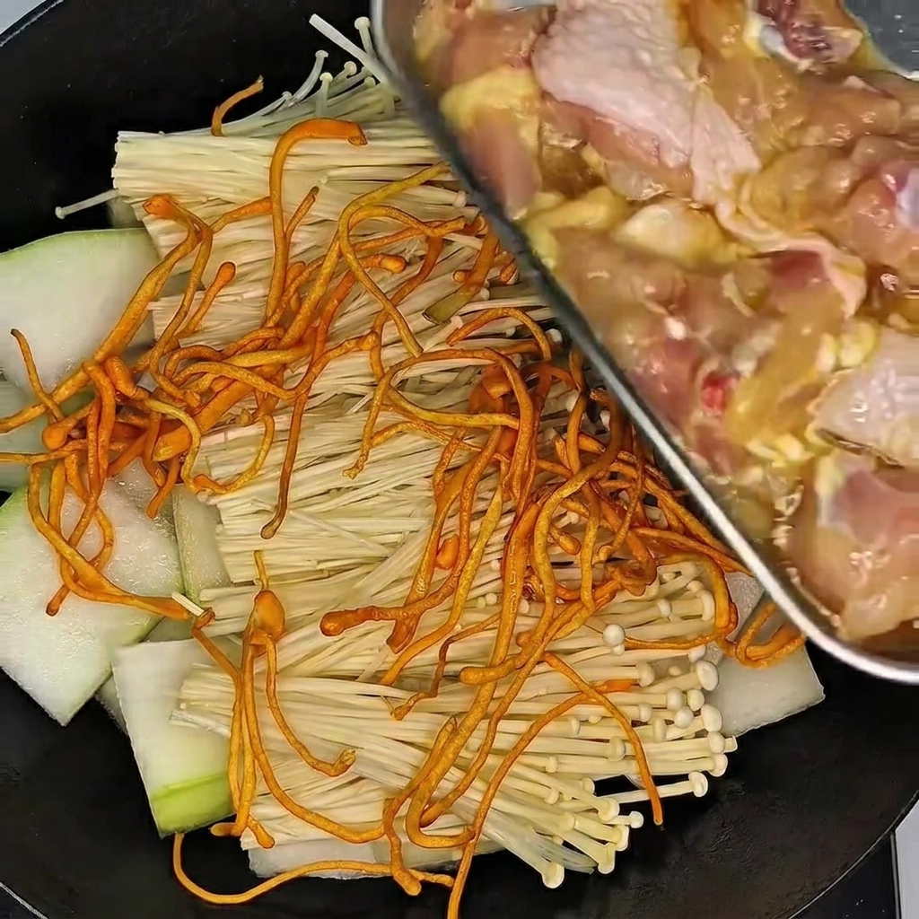 Eine behandschuhte Hand massiert die Hähnchenkeulen in einer Schüssel mit Marinade.