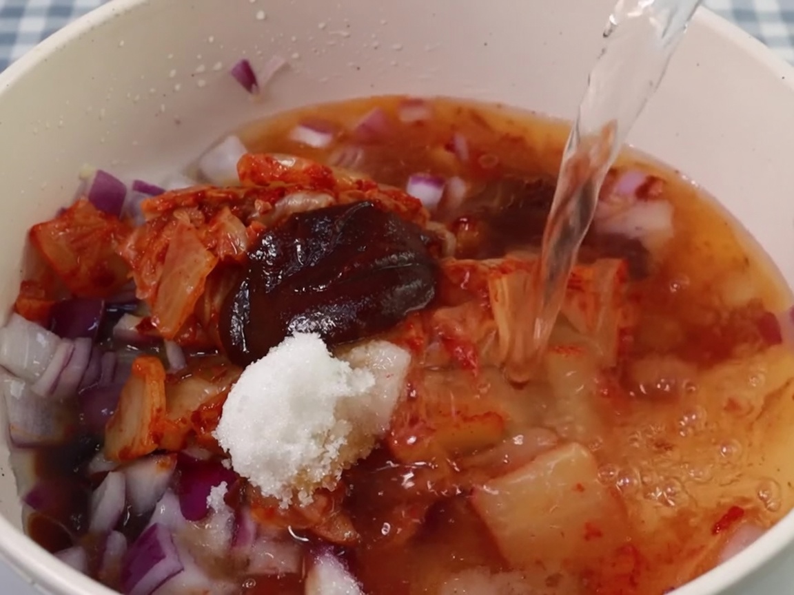 Wasser wird in den Topf zur Kimchi- und Gewürzbasis gegossen.