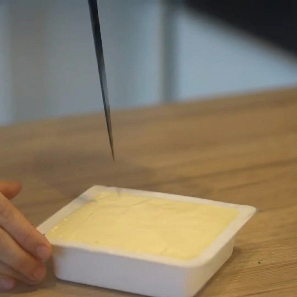 Tofu wird direkt in der Verpackung in gleichmäßige Würfel geschnitten.