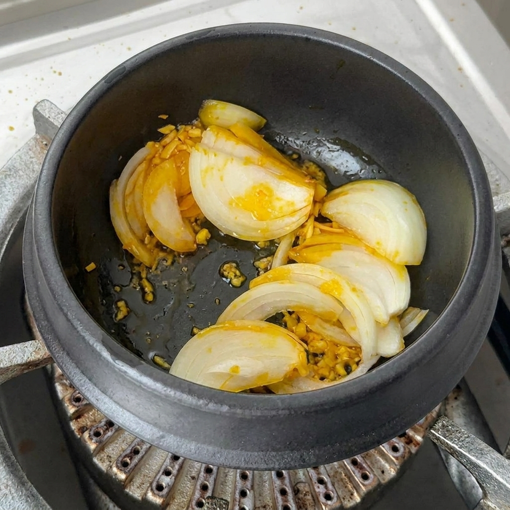 Gehackter Kimchi und rote Chilischeiben werden mit der Basis im Topf vermengt.