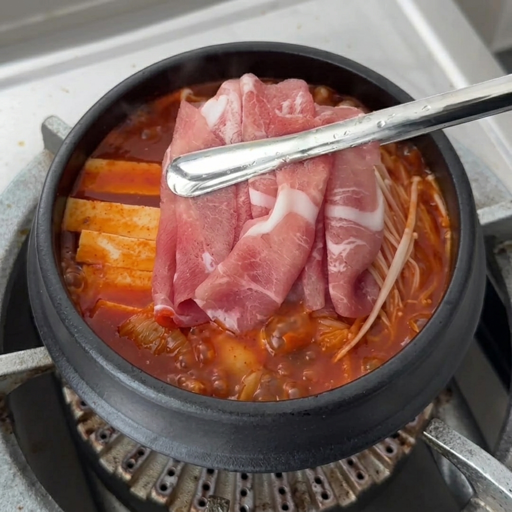 Dünne Schweinefleischscheiben werden oben auf die Zutaten gelegt.