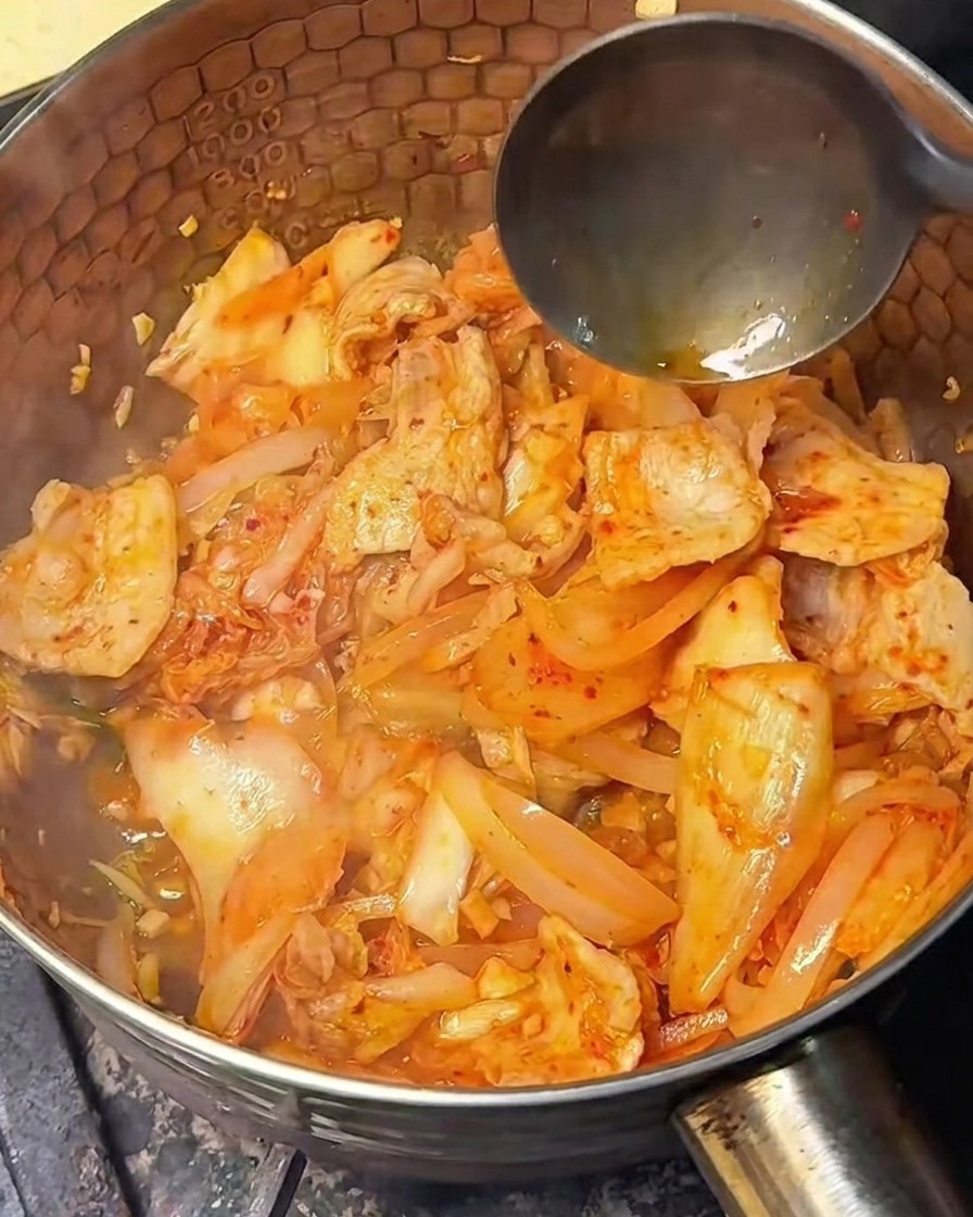 Helle Sojasauce wird über die angebratene Kimchi-Fleisch-Mischung gegossen.