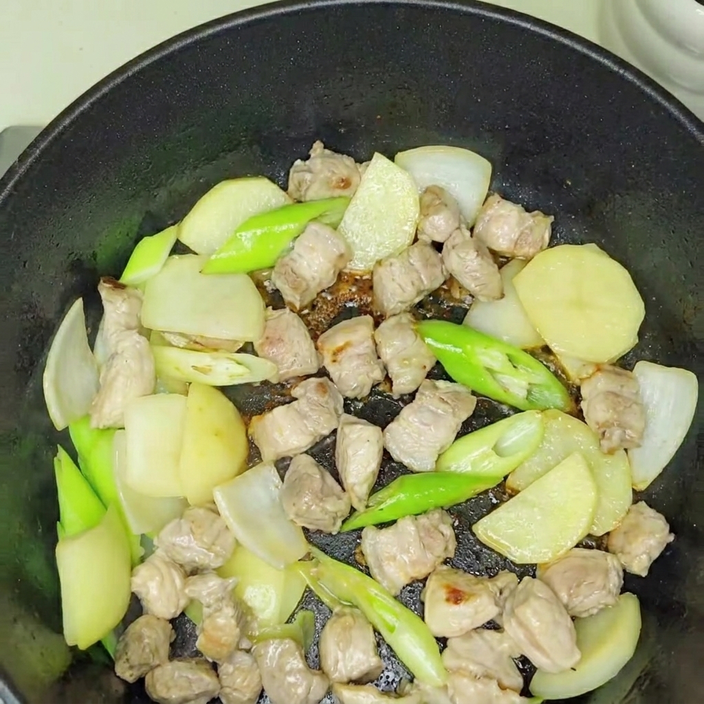 Frisch hinzugefügtes Kimchi wird in die angebratene Fleisch-Zwiebel-Basis eingerührt.